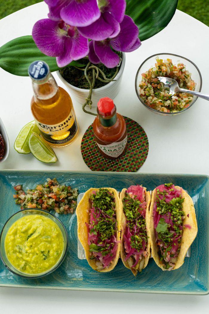 A vibrant Mexican food display with tacos, salsa, guacamole, and beer.