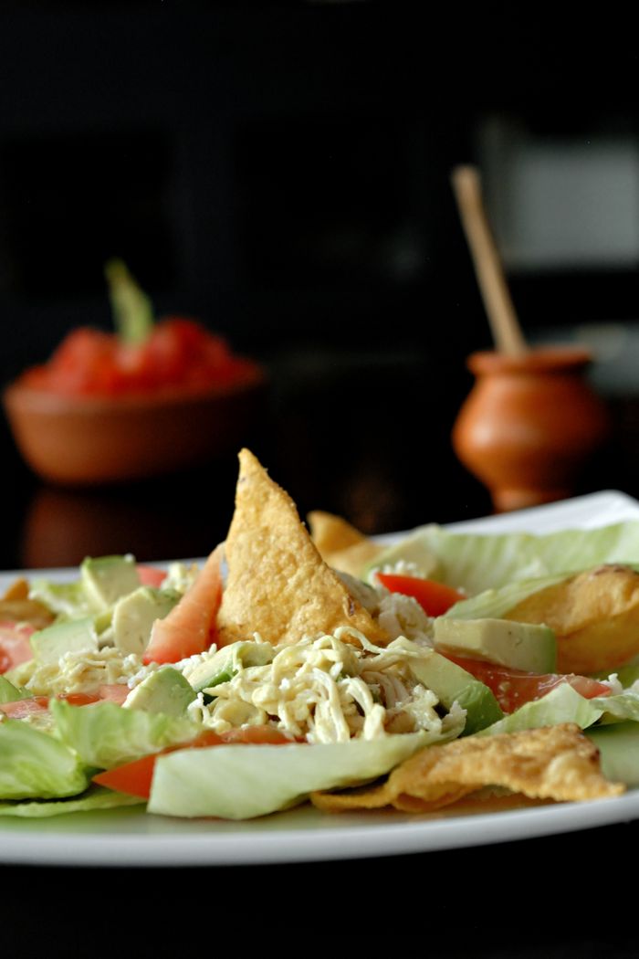 Appetizing Mexican salad with fresh avocado, lettuce, chips, and cheese, creatively plated.
