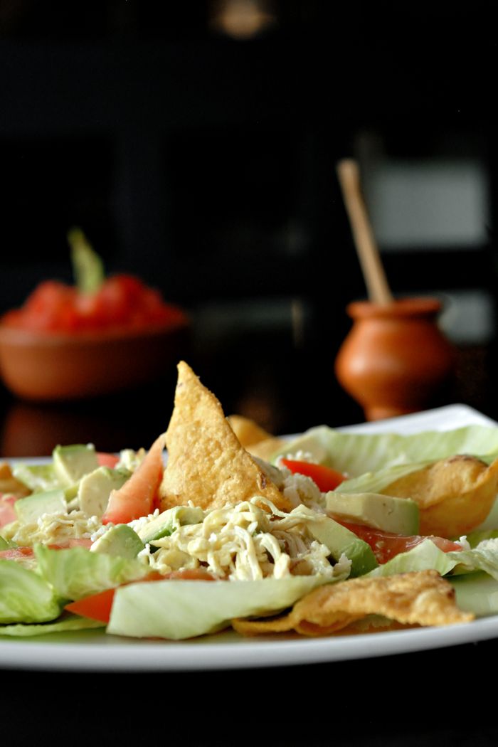 Delicious Mexican salad featuring fresh avocado, nachos, and tomato on a plate, perfect for a healthy meal.